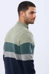 Buzo tejido de punto con diseño de rayas horizontales en tonos verde, gris y azul. Presenta cuello alto con cierre frontal parcial y detalle en material tipo gamuza en la solapa del cierre.