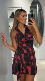 Vestido corto con estampado abstracto en tonos rojo y negro, con escote halter y cuello drapeado.