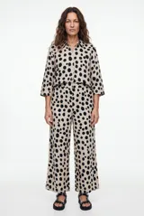 Pantalon tipo palazzo color negro con estampado paisley en tonos beige y blanco, corte holgado y tiro medio.