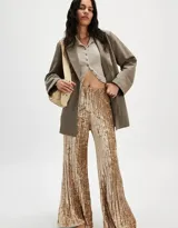 Pantalón de terciopelo color dorado, de tiro alto, silueta amplia y acampanada, con cintura elástica y pliegues en toda la prenda.