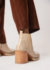 Botín de cuero color beige con textura reptil, elástico lateral y cierre interno. Tiene plataforma delantera y taco de madera.