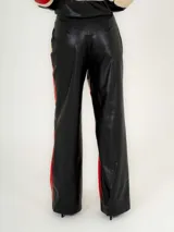 Pantalón de cuero sintético negro con paneles en rojo y beige.
