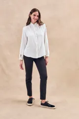 Blusa negra con cuello mao, calce al cuerpo y mangas 3/4 con puños abotonados. Cierre frontal con botones.