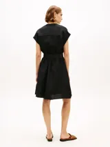Vestido camisero corto negro confeccionado en mezcla de lino y viscosa, con cuello en V, manga tipo kimono, bolsillos con solapa en el pecho y cintura fruncida con cinturón incorporado con hebilla dorada.
