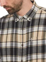 Camisa de franela a cuadros en tonos beige, negro y blanco. Tiene cuello abotonado, manga larga, bolsillo en el pecho y corte clásico.