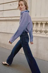 Camisa de corte clásico con cuello solapa y manga larga, confeccionada en tejido oxford con diseño de rayas verticales en azul y bordó. Presenta cierre frontal con botones y bajo con aberturas laterales.