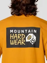 Camiseta de manga corta color mostaza con cuello redondo. Presenta un pequeño logo de Mountain Hardwear en el pecho izquierdo y un gráfico grande enmarcado en la espalda.