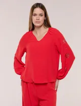 Blusa roja de manga larga con escote en V, calce fluido y detalles de calados en forma de flores en las mangas.