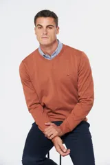 Suéter de tejido fino color azul marino, con cuello en V y manga larga. Presenta un pequeño logo bordado en el pecho.