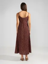 Vestido largo de corte fluido con escote en V profundo y finos breteles. Presenta un estampado animal print combinado con rayas y un detalle decorativo de flor en cobre en el centro del escote.