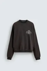 Sudadera de corte relajado color negro con efecto lavado, cuello redondo, manga larga y puños en rib. Presenta un estampado gráfico a contraste en el pecho con el texto 'General Service Goods'.