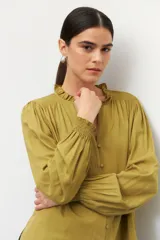 Camisa blanca de manga larga con puños elastizados, cuello mao y escote en v, botones forrados en la misma tela.