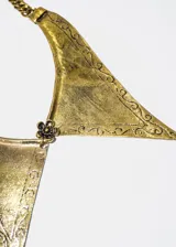Collar dorado de aleación de metales con dije grande de forma triangular con puntas y flor al centro.