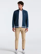 Campera deportiva azul marino de tejido doble con cierre frontal, cuello alto y bolsillos laterales. Presenta rayas blancas en el pecho, hombros y puños, y logo bordado de la marca en el pecho.