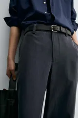 Pantalón de vestir negro, corte recto y relajado, con cintura elástica, cierre frontal con cremallera y botón, bolsillos delanteros y bolsillos traseros de plastrón.