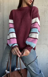 Sweater de tejido de punto con cuello redondo, cuerpo en color bordeaux y mangas con diseño de rayas horizontales en tonos bordeaux, blanco, rosado y celeste.