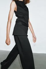 Top de algodón color beige con cuello recto, mangas asimétricas y detalle de tejido drapeado en el frente.