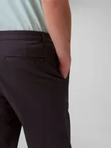 Pantalón de corte slim confeccionado en mezcla de algodón elástico, con cierre de botón y cremallera, diseño de cinco bolsillos y estilo versátil.