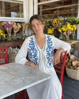 Chaleco blanco de algodón con bordados botánicos en azul índigo, escote en V y cierre frontal con lazos.