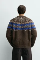 Jersey de punto con diseño jacquard geométrico en la parte superior, cuello redondo y manga larga. Presenta un corte relajado con acabados en rib en puños y ruedo.