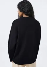 Buzo de punto negro con cuello redondo acanalado, mangas largas con puños ajustados y diseño holgado.