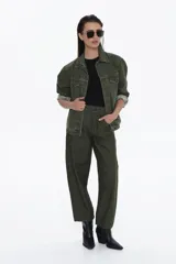 Chaqueta estilo denim oversized color verde militar, con cuello camisero, bolsillos delanteros con tapa y botones frontales. Las mangas son largas y se ven remangadas.