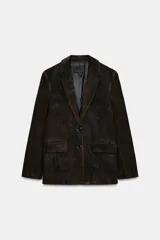 Blazer de piel de ante color marrón con efecto envejecido, solapas con muesca, cierre frontal de dos botones y bolsillos con solapa en el delantero. Cuenta con forro interior y costuras marcadas.