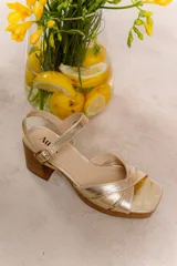 Sandalias negras de cuero charol con tiras cruzadas, plataforma delantera y taco cuadrado. Cierre con hebilla al tobillo.