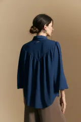 Camisa de manga larga con caída fluida, diseño de silueta suelta, cuello clásico y cierre frontal con botones.