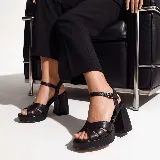 Sandalias de cuero vacuno color negro, con plataforma delantera, taco ancho alto y tiras cruzadas en la parte delantera. Cuentan con tira ajustable con hebilla metálica en el tobillo.