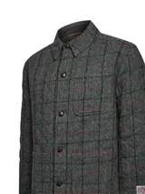 Chaqueta de lana Harris Tweed color gris con patrón de tartán, cuello camisero, cierre frontal de botones y bolsillos aplicados.