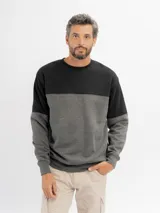 Buzo de felpa de diseño colorblock con cuello redondo, mangas largas y puños de rib, combinando negro en la parte superior y azul en la inferior y mangas.