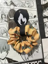 Scrunchie de tela color amarillo con estampado de Calamardo, hecho a mano.