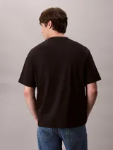 Remera Calvin Klein negra de corte relajado, manga corta y cuello redondo. Presenta un gráfico abstracto estampado en bloques con el logo de la marca en el pecho.