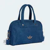 Minibolsa tipo bowling de Adidas Originals confeccionada en denim azul, con asas superiores, correa de hombro desmontable, cierre de cremallera y detalle del logo Trefoil metálico en el frente.