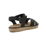 Sandalias de mujer color negro, con tiras cruzadas en el empeine, ajuste elástico en el tobillo y suela plana marrón claro.