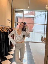 Top de tejido jacquard blanco con estampado floral en gris, escote en V y mangas acampanadas.