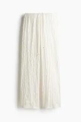 Pantalón de corte holgado con textura efecto encaje, tiro bajo y piernas extralargas. Cuenta con cintura elástica y cordón ajustable.
