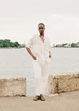 Jeans blancos de corte recto y tiro medio, confeccionados en tejido denim de algodón. Presenta diseño crop con bajo deshilachado, estilo clásico de cinco bolsillos, trabillas para cinturón y cierre frontal con cremallera y botón metálico.
