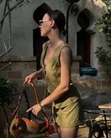 Conjunto de dos piezas color verde oliva con textura arrugada. Incluye un chaleco sin mangas con cierre frontal de lazos y una minifalda ajustada.