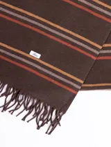 Bufanda de tejido suave en color marrón chocolate con diseño de rayas horizontales en tonos naranja, beige y gris. Presenta terminaciones con flecos en los extremos.