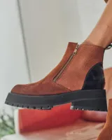 Bota corta de cuero color marrón con puntera redondeada, cierre lateral con cremallera dorada y detalle de charol negro en el talón. Suela de goma negra con plataforma.