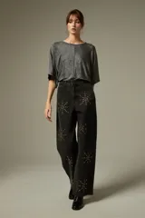 Pantalón de jean negro de corte ancho y tiro alto, decorado con aplicaciones de strass formando estrellas en toda la superficie.