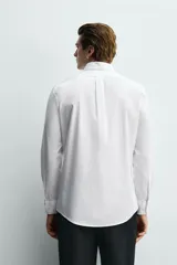 Camisa regular fit de algodón con diseño de rayas finas celestes y blancas. Cuenta con cuello abotonado, manga larga con puños abotonados y cierre frontal de botones.