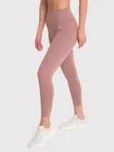 Calza deportiva de tiro alto con largo hasta el tobillo, confeccionada en tejido elástico de color rosado tierra. Presenta un diseño minimalista sin bolsillos y un pequeño logo bordado en la cadera.