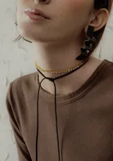 Gargantilla choker con tira de strass dorados y tiento de cuero negro para atar.