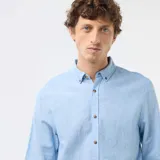 Camisa de manga larga en color azul cielo, confeccionada en mezcla de lino con botones frontales imitación madera y cuello con botones.