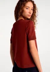 Blusa de manga corta confeccionada en tejido de punto, color negro, con cuello redondo y diseño clásico.