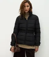 Campera puffer acolchada de color negro con pespuntes horizontales, cuello alto, cierre frontal y cinturón integrado ajustable para entallar la silueta.