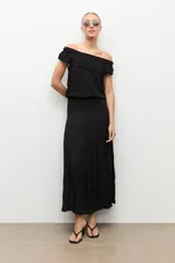 Blusa negra estilo bardot con escote de hombros descubiertos, detalles de volados fruncidos en el pecho y diseño sin mangas.